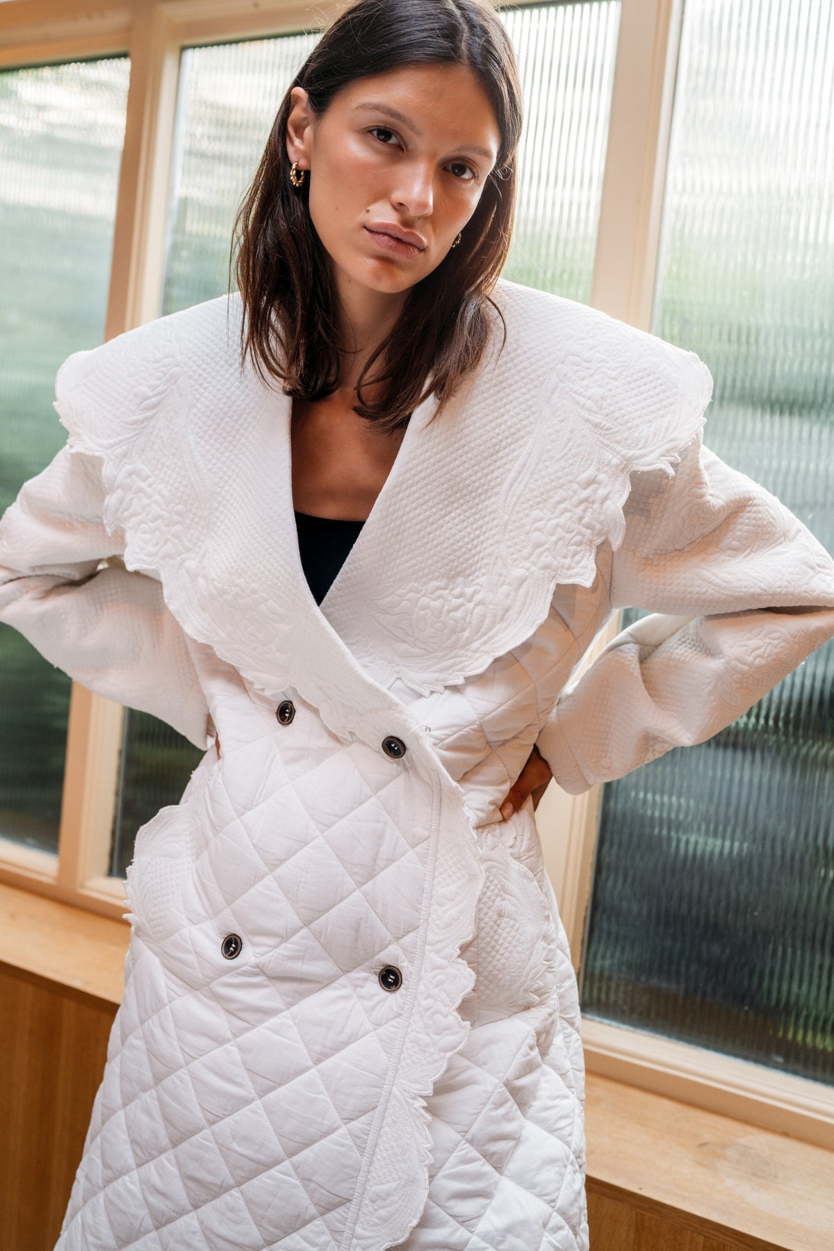 Close up shot of a girl wearing a quilted ivory trench coat.